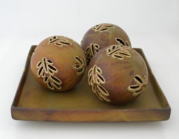 tan color stoneware decoration balls with pierced branch on dish, esferas decoradas con rama calada color cafe sobre plato cuadrado